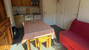 A compact kitchen with wooden cabinets, a microwave, and a dining area with a table and bench.