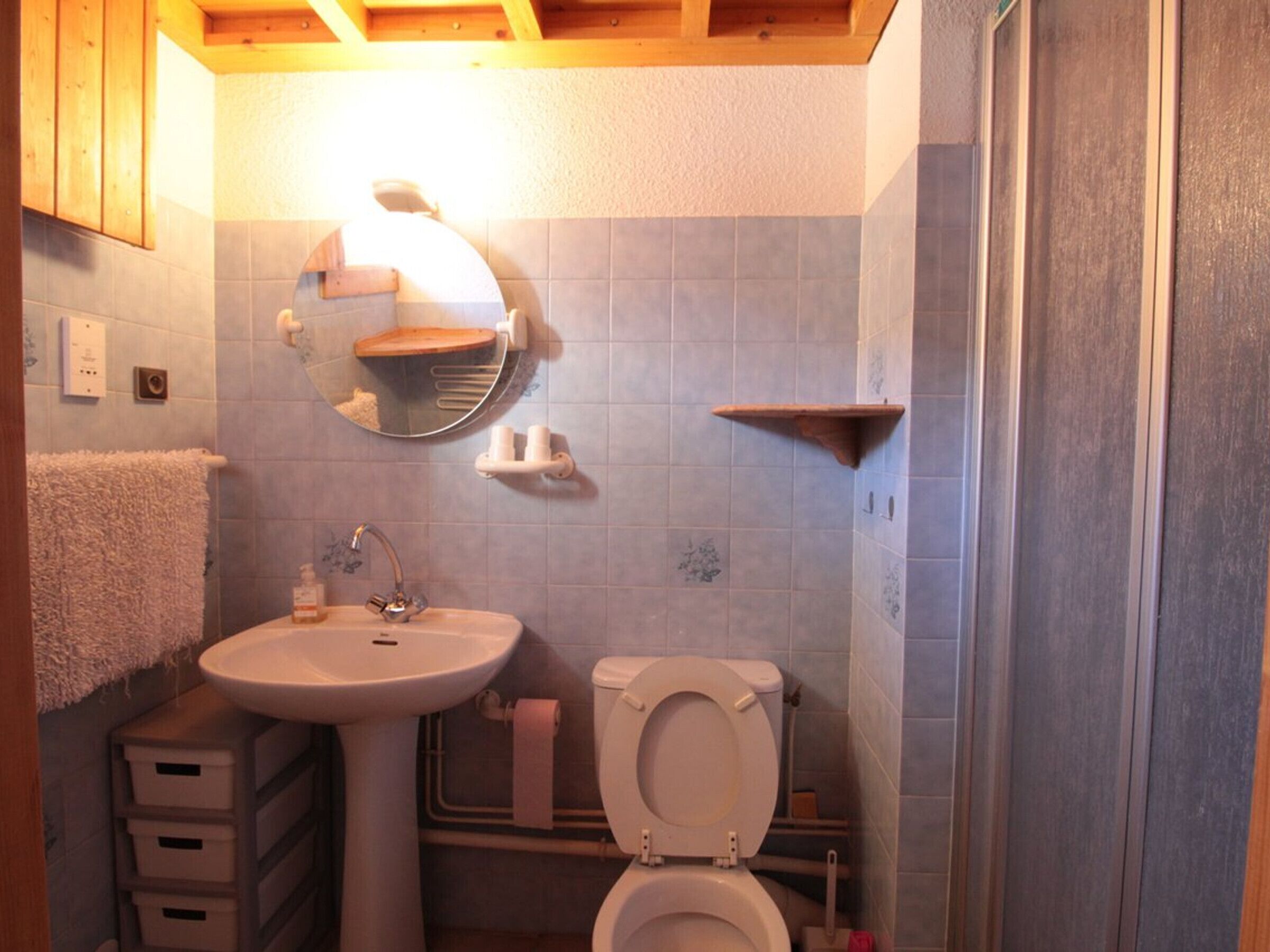 Une salle de bain avec un lavabo, des toilettes et un miroir. Elle comprend des tiroirs de rangement et un porte-serviettes.