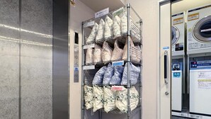 A laundry facility with multiple washing machines and shelves of laundry bags. - Hotel Trend Omiya (Saitama)