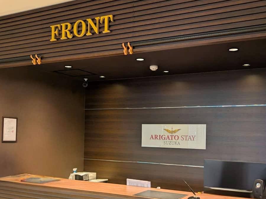 Un mostrador de recepción con un cartel que dice "FRONT" y "ARIGATO STAY SUZUKA".