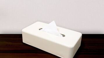 Una caja de pañuelos blancos sobre una superficie de madera, con un pared lisa de fondo.