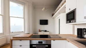 A modern kitchen with a large window, built-in appliances, and a flat-screen TV. - Immaculate 1-bed Apartment on Hove Seafront (Hove)
