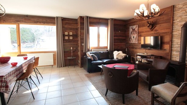 A cozy living room with a fireplace, a television, and a dining area with a table and chairs. - 3-bedroom apartment, 2 bathrooms, parking, near slopes, equipped with high standards (Les Carroz d'Arâches)