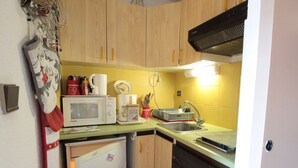A compact kitchen with a microwave, coffee maker, and sink.