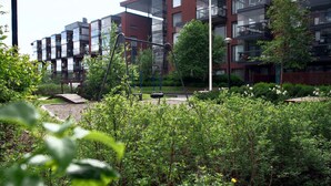Un edificio residenziale moderno con numerosi balconi e un'area giardino curata, con altalene.