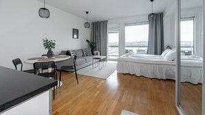 Un appartamento moderno con zona pranzo, divano, letto e ampie finestre che offrono vista sulla città.