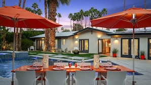 A modern house with a pool, dining area with red umbrellas, and a well-maintained garden. - Mountain Views, Pool and Near Downtown (Palm Springs)