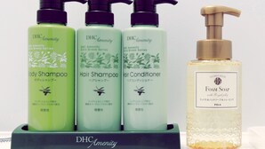 Ein Satz mit drei Amenity-Flaschen der Marke DHC und eine Flasche Schaumbadseife.