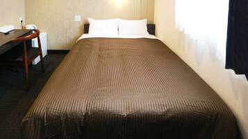 A hotel room with a bed, a desk, and a chair.