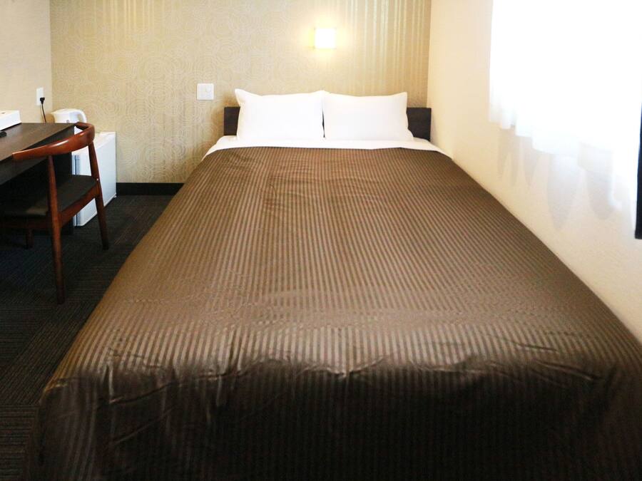 A hotel room with a bed, a desk, and a chair.