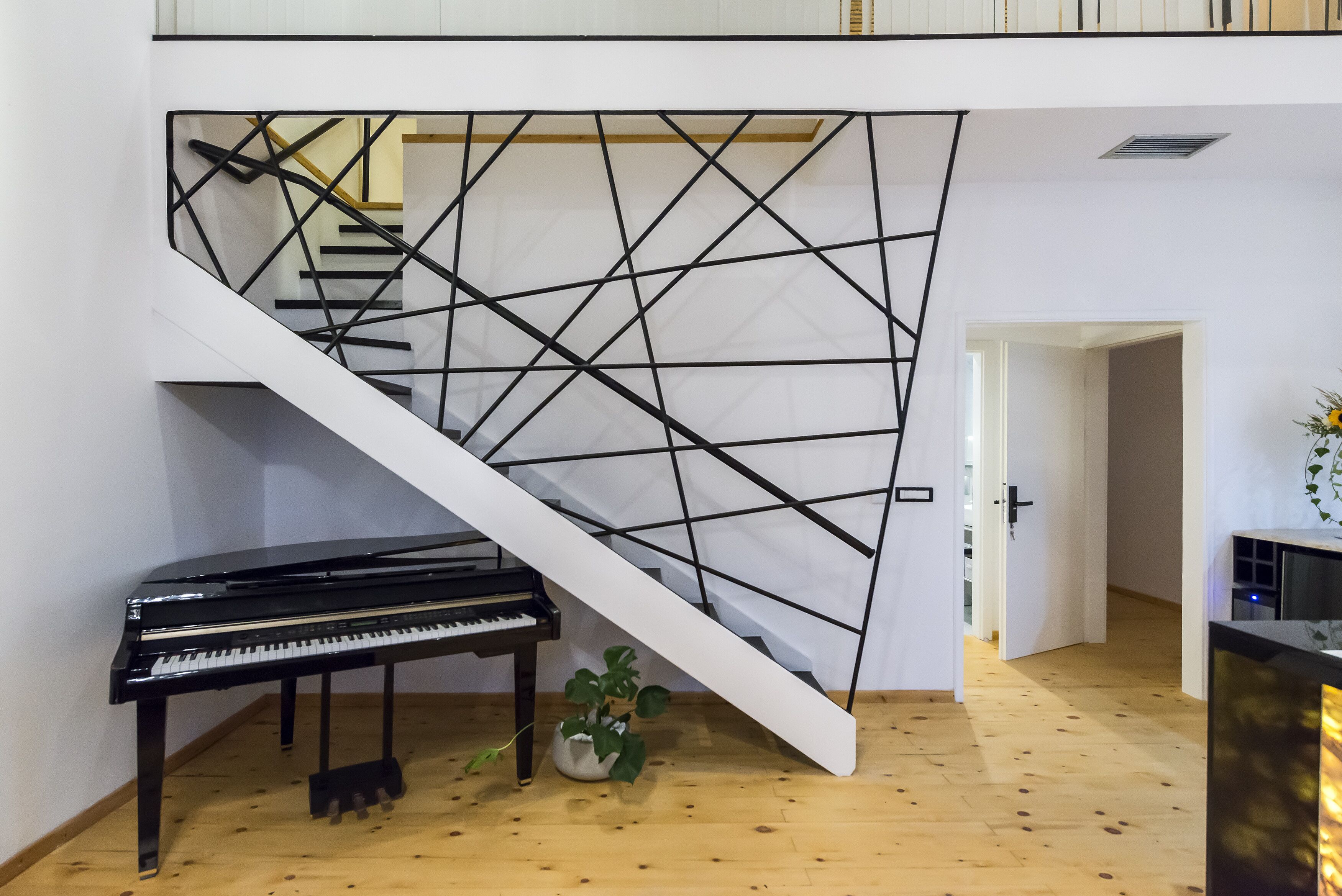 A piano near a staircase with a geometric-patterned wall.