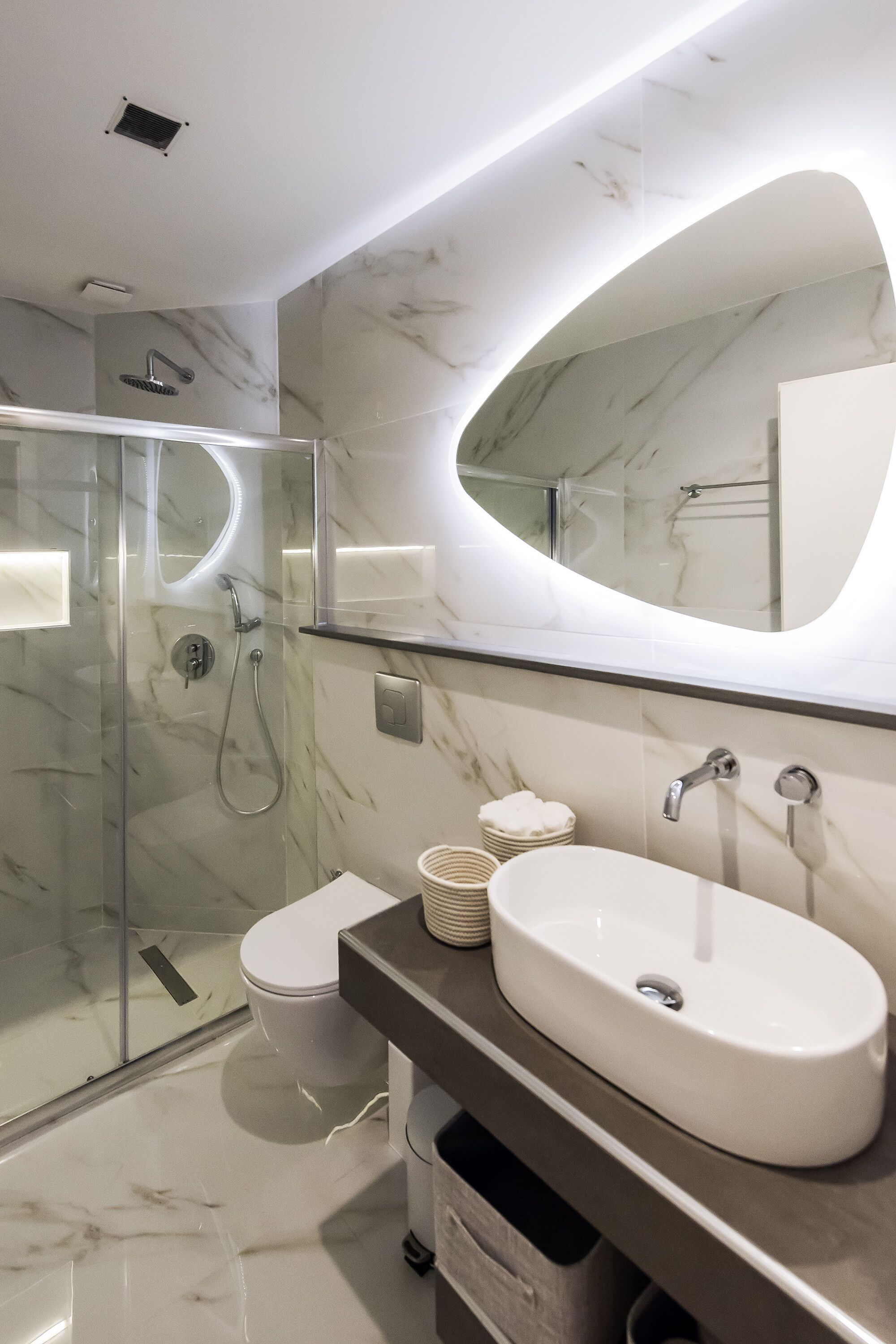 A modern bathroom with a glass-enclosed shower, a white sink, and a large mirror.