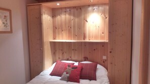 Ein Schlafzimmer mit einem hölzernen Kopfende, einem Bett mit weißer Bettwäsche und zwei roten Kissen.