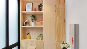 A reception desk with wooden shelving, a potted plant, and a small table. - Dandelion (Tokyo)