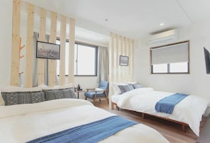 A hotel room with two beds, a chair, a TV, and a large window.