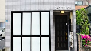 A building with a large glass facade and a black door. - Dandelion (Tokyo)
