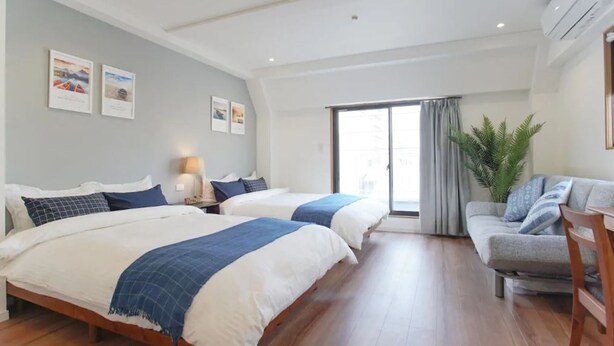 A hotel room with two beds, a sofa, a desk, and a large window with curtains. - Dandelion (Tokyo)