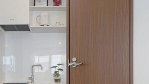 A modern kitchen with a white countertop, stainless steel faucet, and a potted plant. - Dandelion (Tokyo)