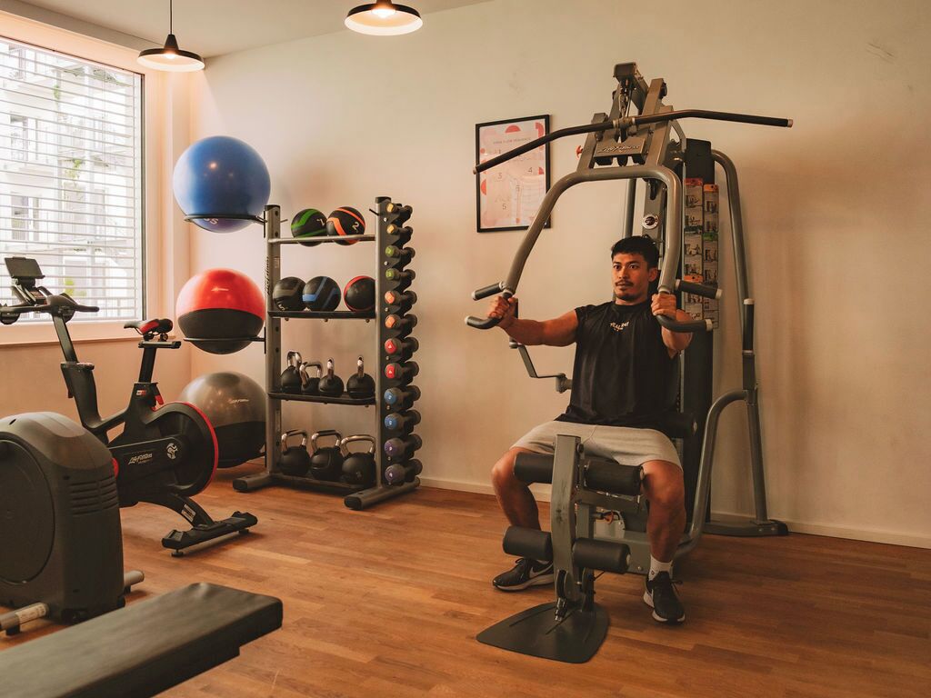 A gym with exercise equipment, a treadmill, and a rack of kettlebells.