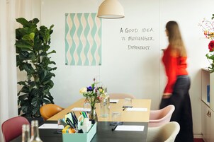 Quarto moderno com uma mesa de madeira, cadeiras, planta em vaso e parede com padrão decorativo.