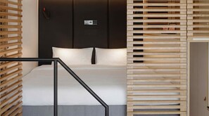 A modern bedroom with a bed, a control panel, and a wooden partition. - Zoku Vienna (Vienna)
