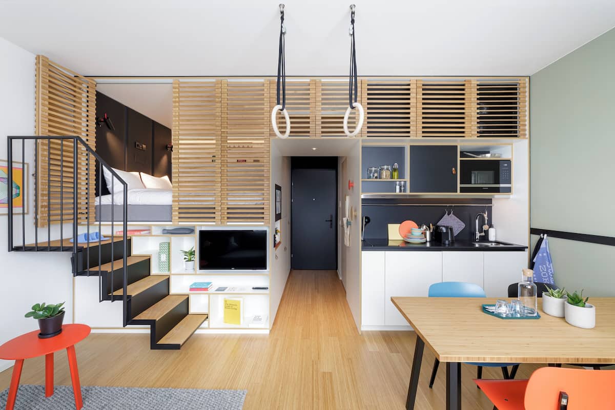 Un espacio habitable compacto con una escalera, una zona de cocina y una mesa de comedor.
