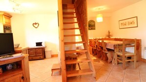 A wooden staircase leading to a dining area with a table and chairs.