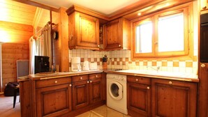 A compact kitchen with wooden cabinets, a washing machine, and a coffee maker.