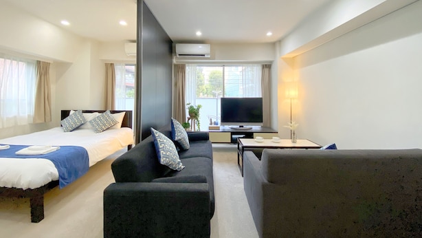 A modern hotel room with a bed, sofa, TV, and a small table. - Pangoo Shinagawa (Tokyo)