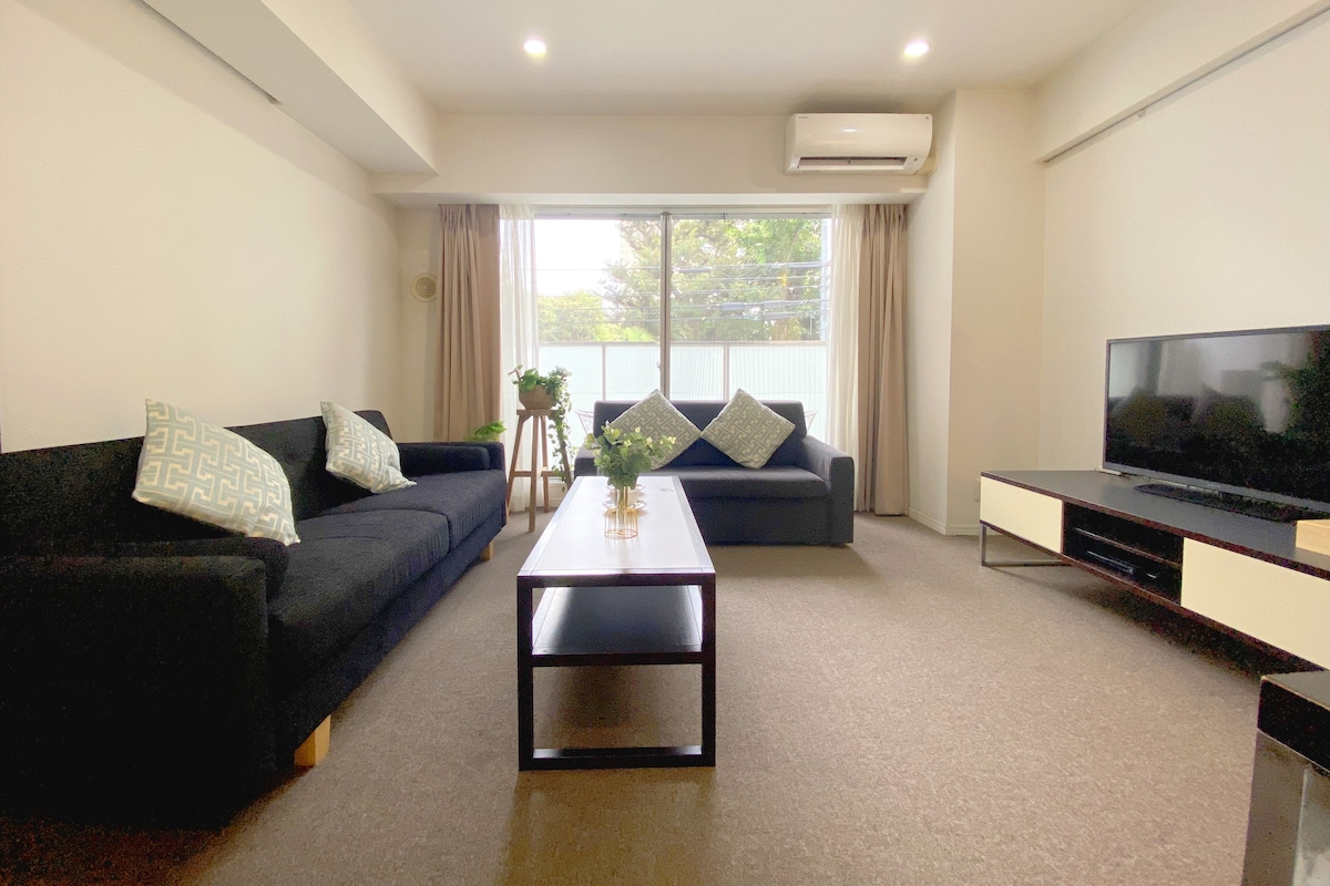 Uma sala de estar moderna com um conjunto de sofás, uma mesa de centro e uma televisão de tela plana.