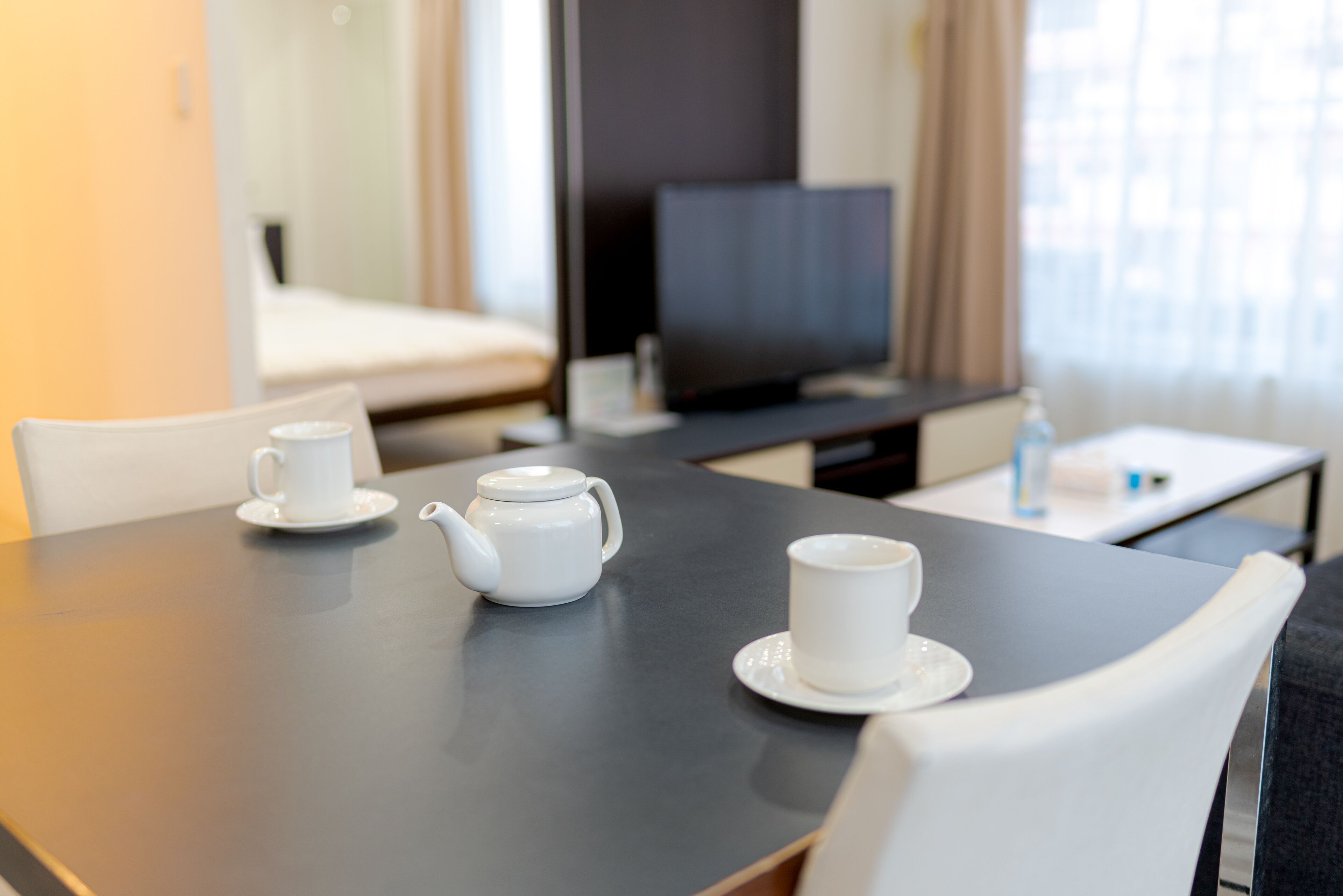 Ett hotellrum med ett matbord dukat för två personer, en tv och en säng i bakgrunden.