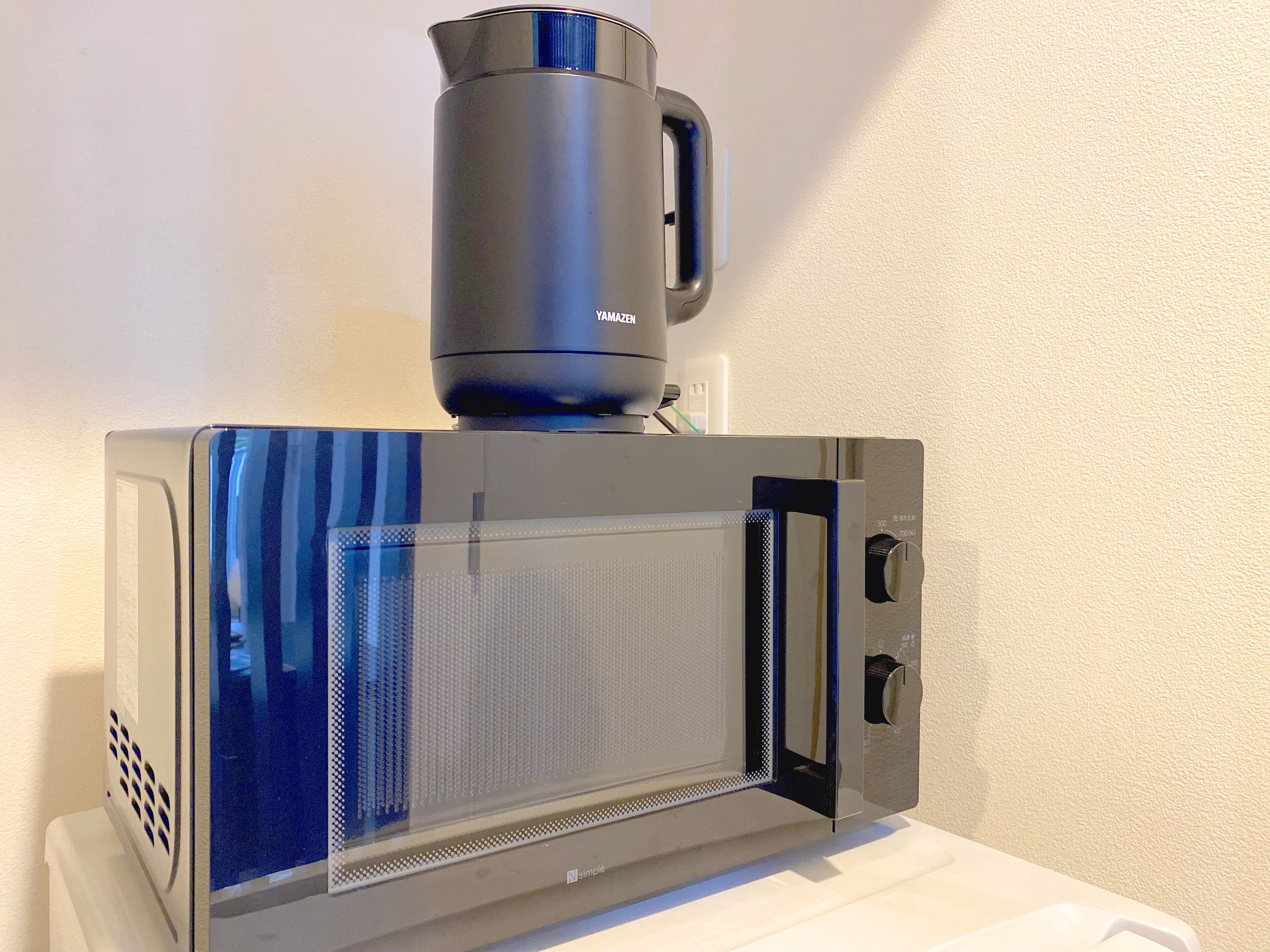 A modern microwave with a digital display and a coffee maker on top.