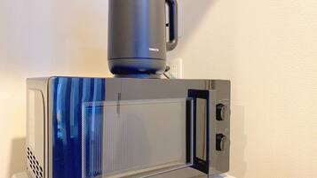 A modern microwave with a digital display and a coffee maker on top.