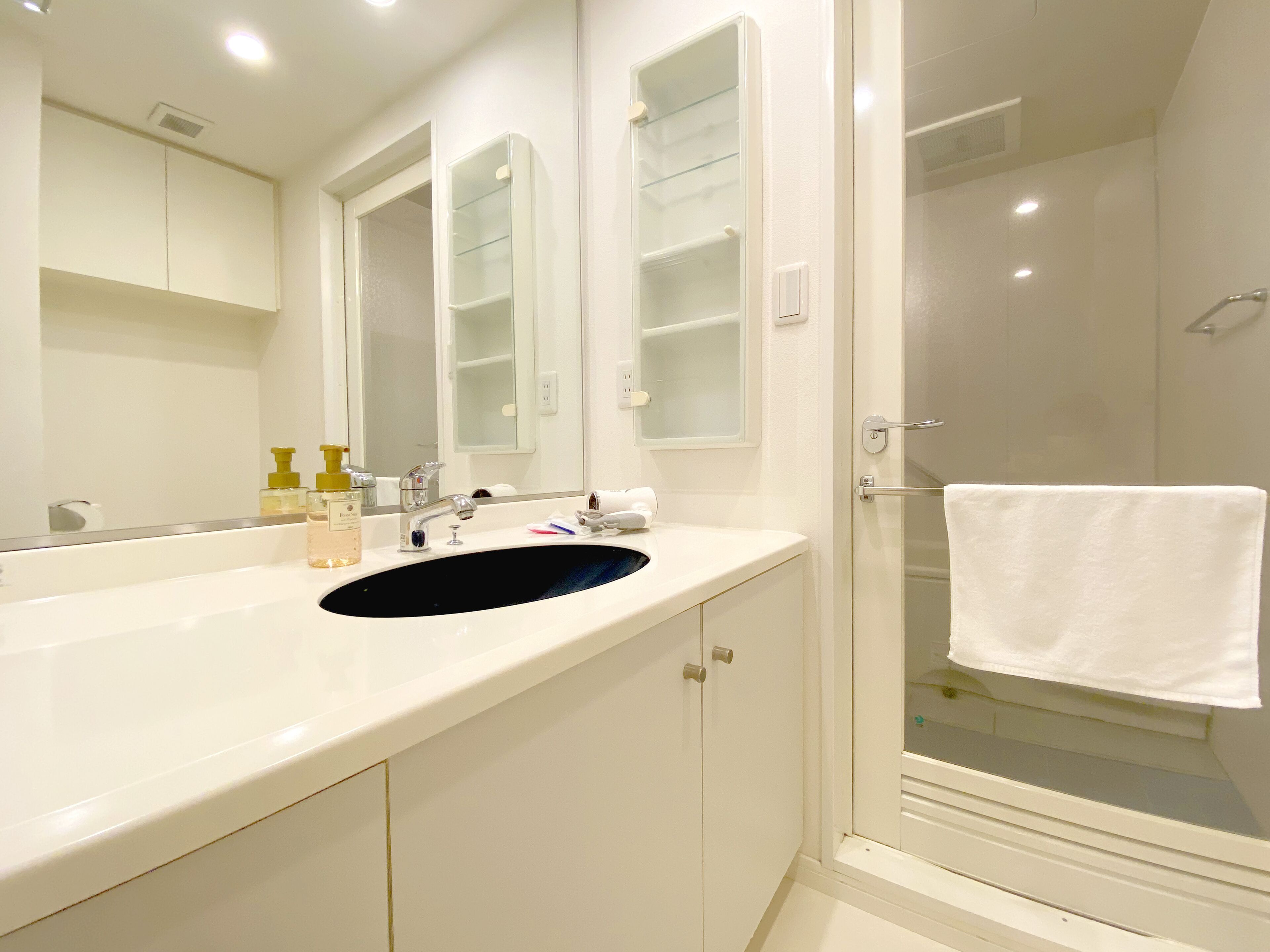 A modern bathroom with a white sink, a mirror, and a glass-enclosed shower.