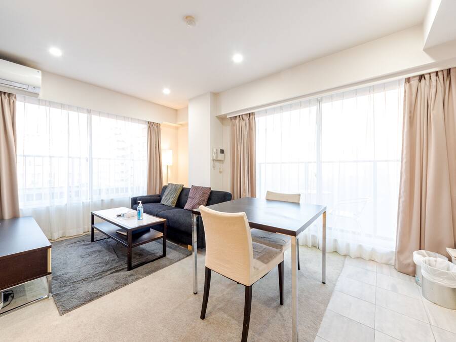 A modern hotel room with a sofa, dining table, and TV.