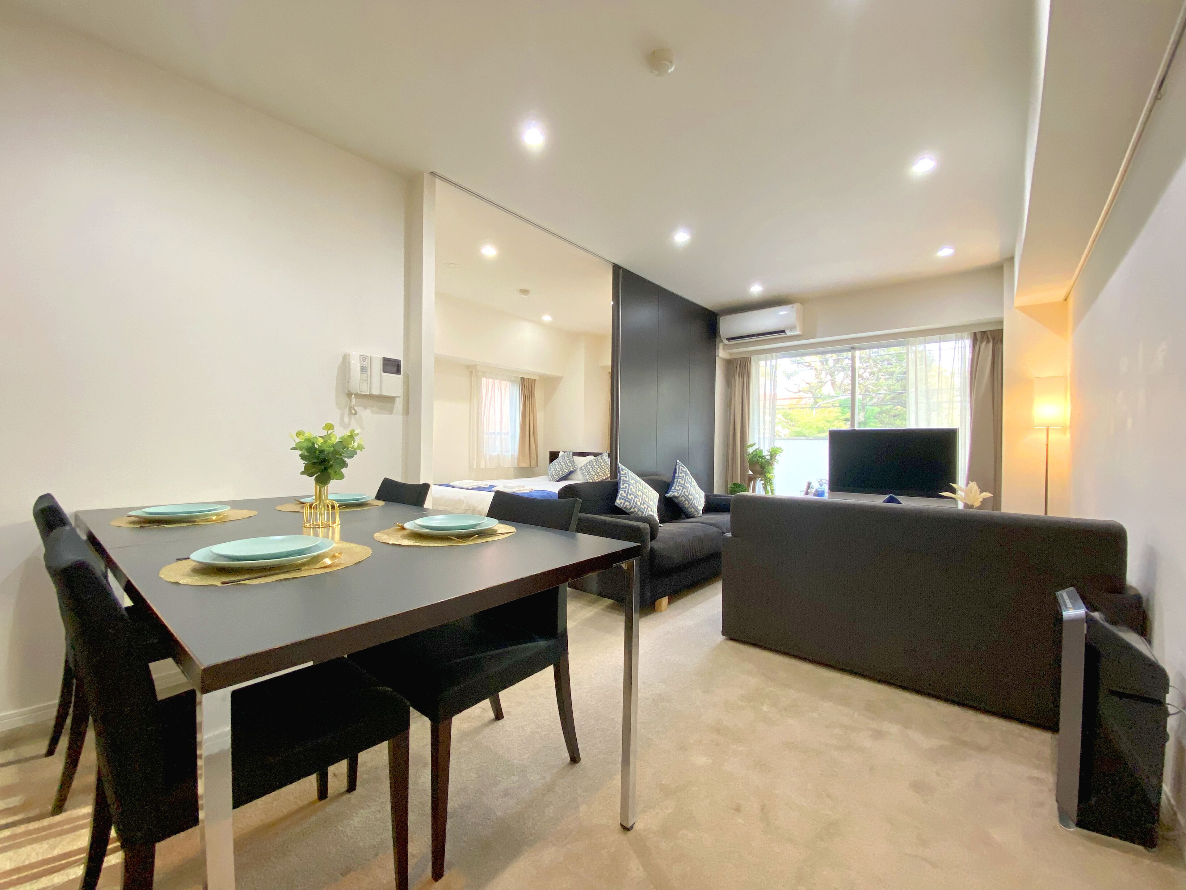 Uma sala de estar moderna com área de jantar, sofá, TV e aparelho de ar condicionado.