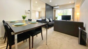 A modern living room with a dining area, a sofa, a TV, and an air conditioning unit. - Pangoo Shinagawa (Tokyo)