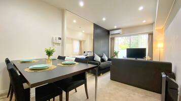 Uma sala de estar moderna com área de jantar, sofá, TV e aparelho de ar condicionado.