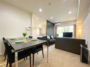 Uma sala de estar moderna com área de jantar, sofá, TV e aparelho de ar condicionado.