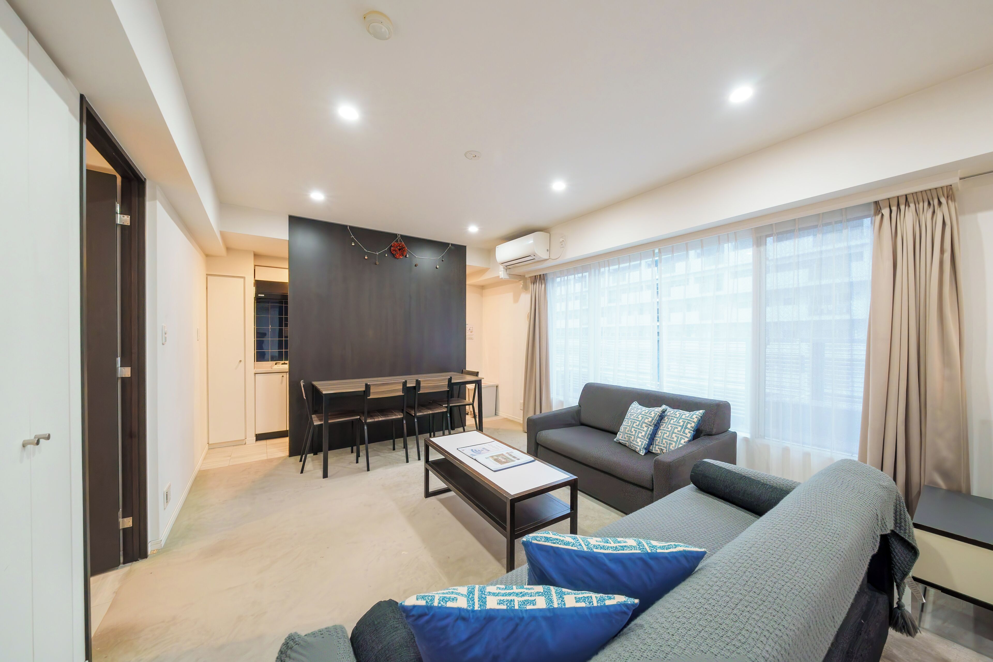 A modern living room with a sofa, coffee table, and dining area.