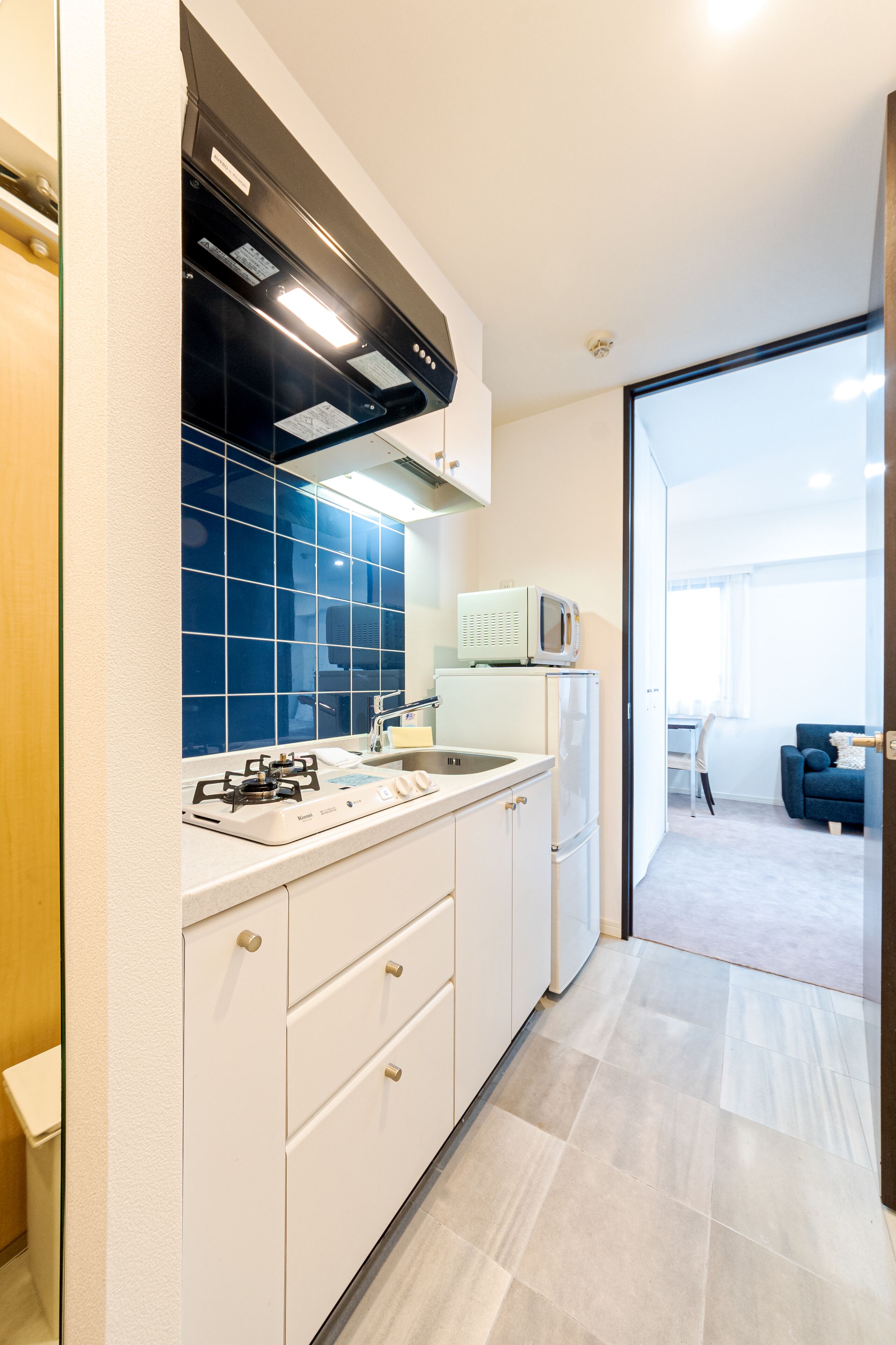 A modern kitchen with white cabinets, a gas stove, a microwave, and a blue-tiled backsplash.