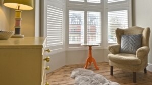 A room with a bay window, a lamp, a chair, a small table, and a rug on a wooden floor. - Rockcliffe Boutique 2-bed Apartment in Whitby (Whitby)