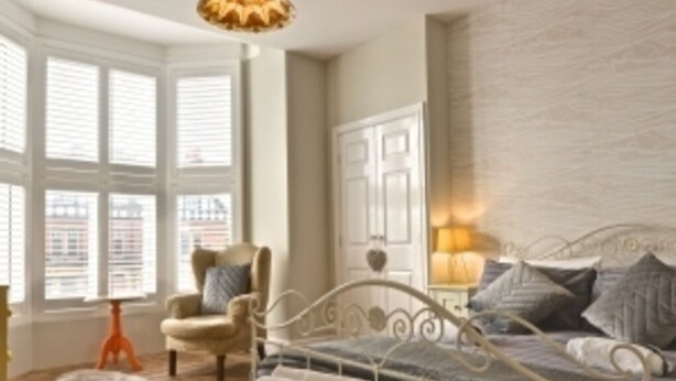 A bedroom with a bed, a chair, a bedside table, and a window with blinds. - Rockcliffe Boutique 2-bed Apartment in Whitby (Whitby)