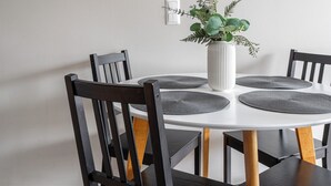 A dining area with a white table, black chairs, and a white vase with green plants. - 1BR Apt and Balcony next to Railway Station (Tampere)