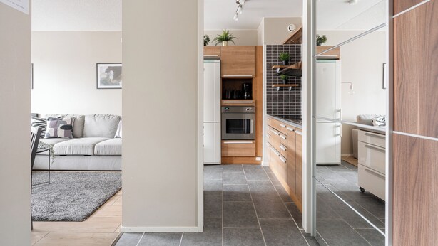 A modern kitchen with a central island, wooden cabinets, and a built-in oven. - 1BR Apt and Balcony next to Railway Station (Tampere)