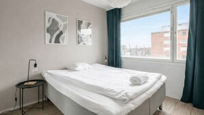 A bedroom with a bed, a bedside table, a lamp, and two abstract paintings on the wall. - 1BR Apt and Balcony next to Railway Station (Tampere)
