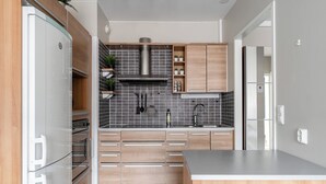 A modern kitchen with wooden cabinets, a stainless steel range hood, and a grey tiled backsplash. - 1BR Apt and Balcony next to Railway Station (Tampere)