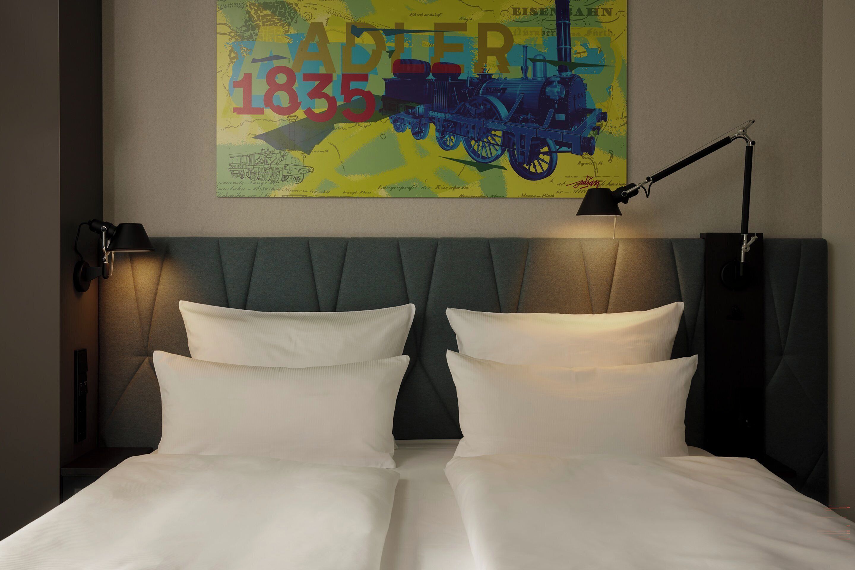 A double bed with two white pillows and a grey upholstered headboard.
