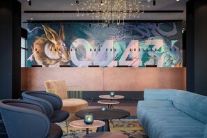 A modern lounge area with a large mural, comfortable seating, and ambient lighting. - The Cloud One Nürnberg, part of the Motel One Group (Nuremberg)