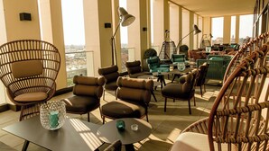 A spacious balcony with wicker furniture, a table with a glass vase, and a view of the city. - The Cloud One Nürnberg, by the Motel One Group (Nuremberg)